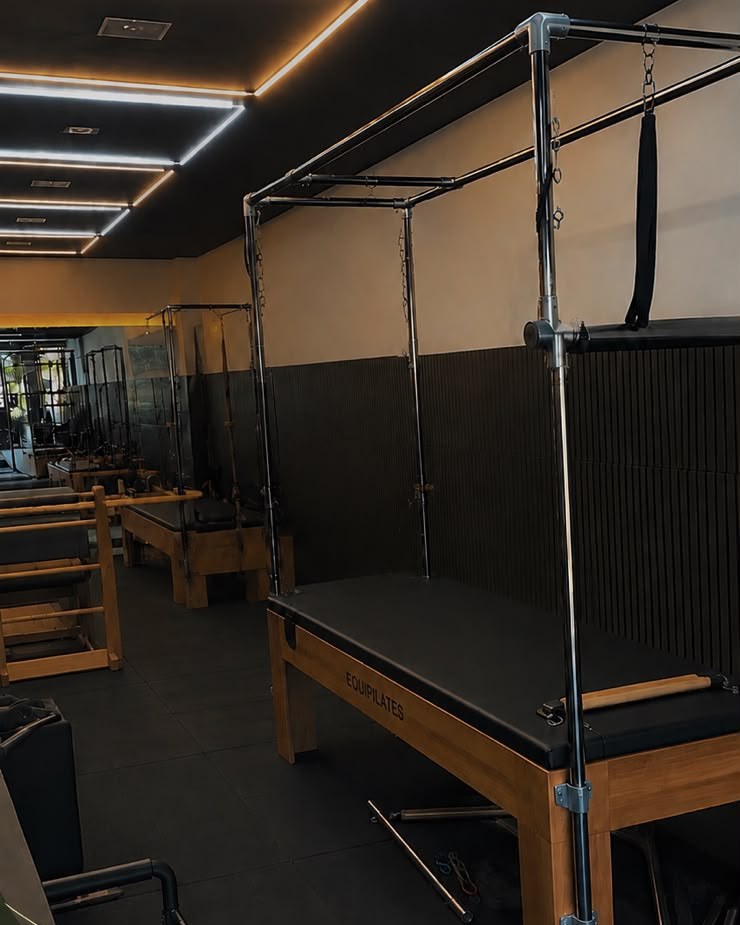 Sala do TH Pilates com cadillac e aparelhos de madeira, luzes em linha no teto